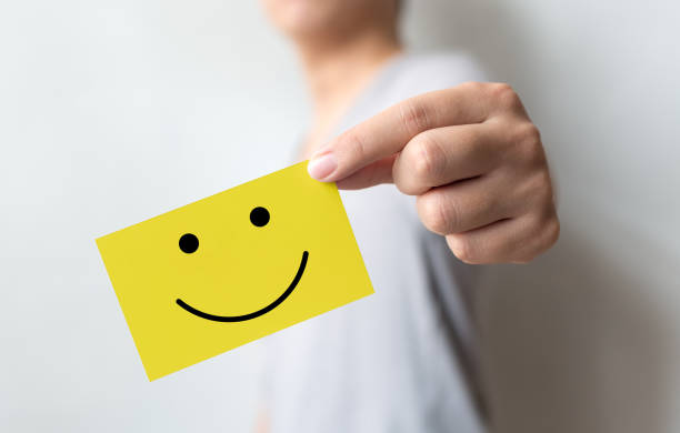 A person holding a yellow card with a smiley face, symbolizing the uplifting power of affirmations.