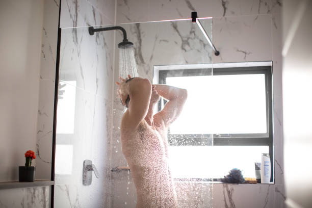 A person taking a shower under running water, representing personal hygiene and the debate on how often should you shower for optimal skin health.