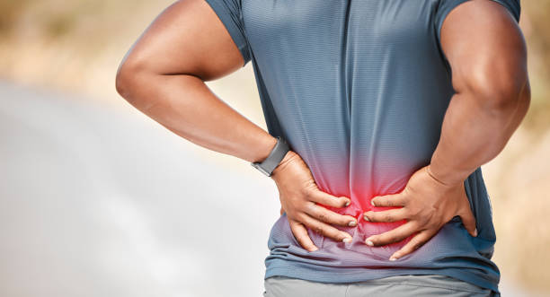 Man holding his lower back in pain, with a highlighted red area indicating discomfort or inflammation.