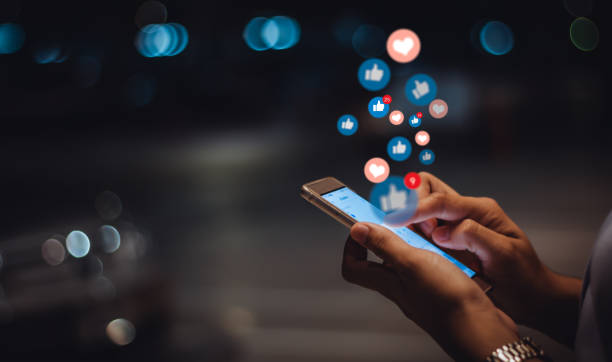 A person engaged in social media use at night, interacting with a smartphone as floating notification icons symbolize digital engagement and online connectivity.