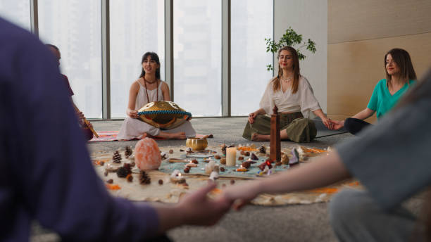 A group of people practicing meditation and sound healing, holding hands in a peaceful setting with candles and crystals.