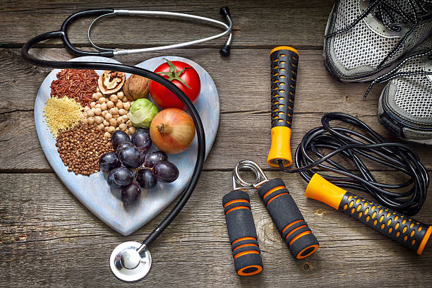 A heart-shaped plate with healthy foods, a stethoscope, and fitness equipment representing sports nutrition and a balanced diet for active lifestyles.