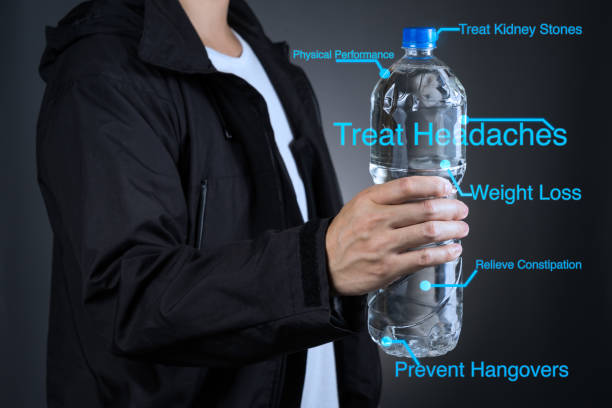 A person holding a bottle of water with digital annotations highlighting its health benefits, including treating headaches, weight loss, preventing hangovers, relieving constipation, and improving physical performance.