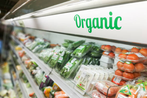 Organic food section in a grocery store with fresh vegetables, fruits, and packaged organic products neatly displayed on shelves.