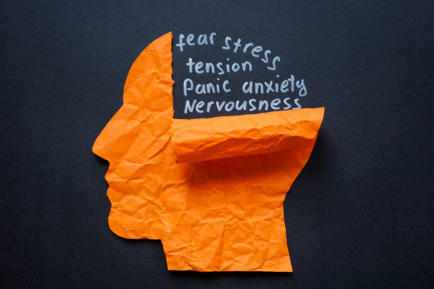 A crumpled paper cutout of a human head with words like fear, stress, anxiety, panic, and nervousness written inside, symbolizing mental distress and trauma.