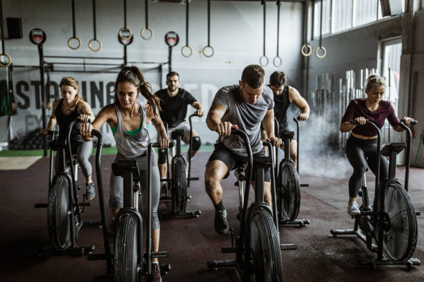 A group of determined individuals cycling intensely in a gym, demonstrating how high-intensity workouts can improve your stamina and build endurance.