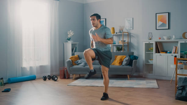 Cardio workout for weight loss – man doing high knees at home, engaging in fat-burning exercise.