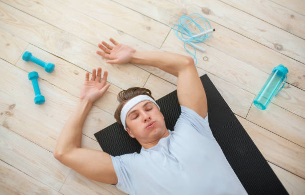 Man lying exhausted on a workout mat after exercise, highlighting how sleep affects your workout performance and overall fitness recovery.