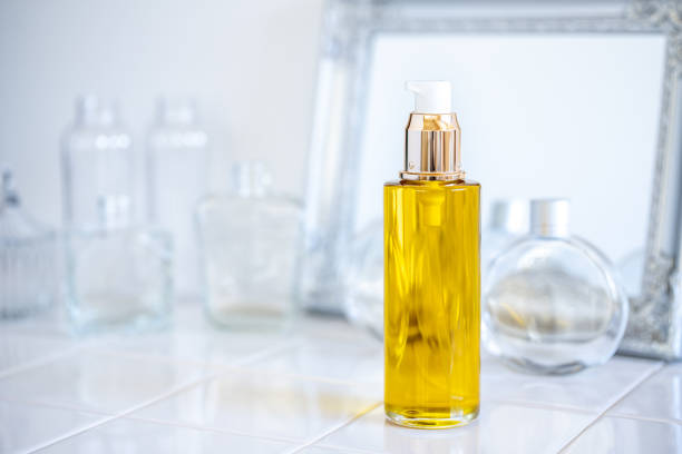 A bottle of luxurious facial oil for nighttime skincare and skin repair, placed on a bathroom counter with a mirror and glass containers in the background.