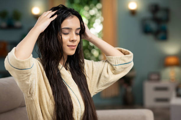 A woman gently massaging conditioner into her wet hair, following the best way to condition your hair for smoothness, hydration, and nourishment.