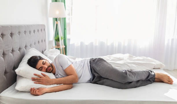 Man sleeping on a comfortable bed, illustrating the benefits of choosing the right mattress for pain-free sleep and improved spinal support.