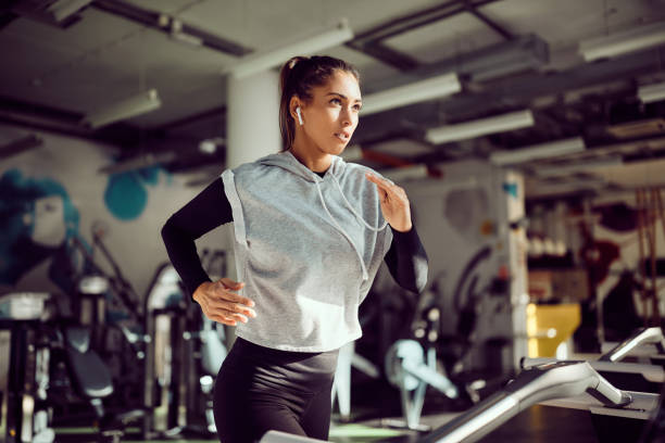 A woman running on a treadmill in the gym, emphasizing cardio workouts for endurance and fat loss.