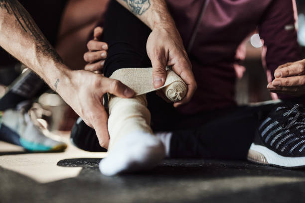 A close-up of a person wrapping a bandage around a sprained ankle, providing support and promoting faster recovery.
