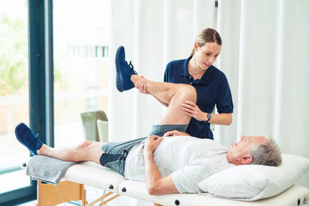 A senior man receiving chiropractic care as a therapist performs a mobility exercise to enhance joint function and pain relief.
