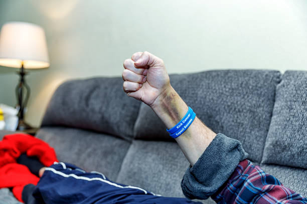 An individual resting on a couch with a raised fist, symbolizing resilience in managing pain from old injuries.