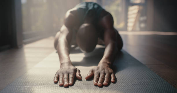 A man in Child’s Pose yoga position on a mat, arms stretched forward, offering deep relaxation and back pain relief.