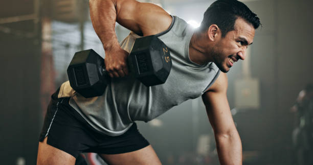 Man performing a one-arm dumbbell row in a gym, demonstrating the benefits of weightlifting for building muscle strength and endurance.