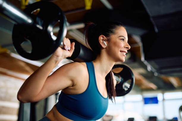 A woman lifting a barbell in the gym, showcasing strength training for muscle building and weight loss.