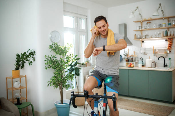 A man cycling indoors and monitoring his progress, engaging in regular exercise to naturally improve insulin sensitivity.