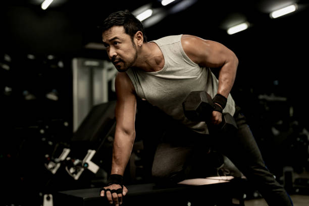 Man performing a single-arm dumbbell row, engaging core exercises for stability and strength without relying on crunches.