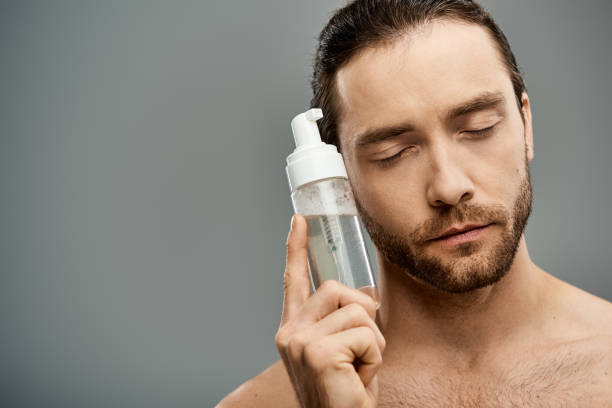 Man holding a facial cleanser with closed eyes, emphasizing the importance of double cleansing for a deep and effective skincare routine.