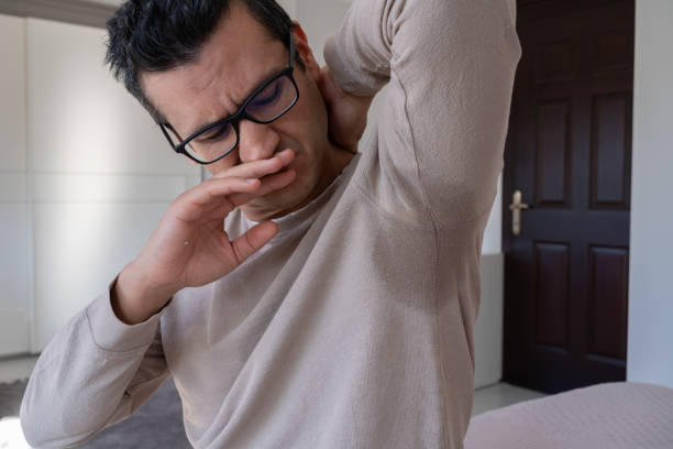 Man reacting to underarm odor in a beige sweater.