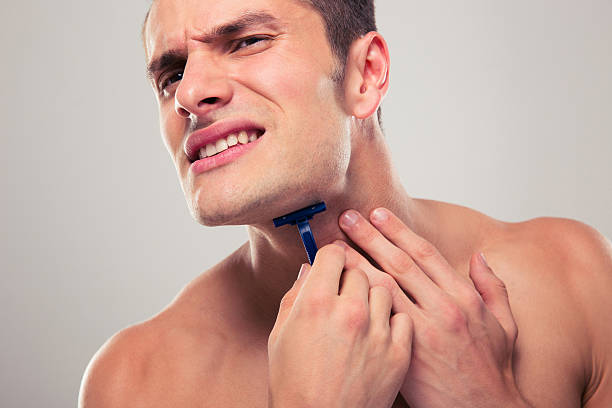 A man experiencing discomfort while shaving, highlighting the struggle to prevent razor bumps and irritation after shaving.