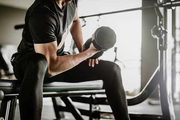 Strength training workout for weight loss – man doing a bicep curl with a dumbbell in a gym.
